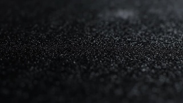 Abstract macro background of dark black granular texture with shallow depth of field