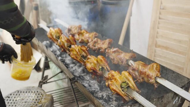 Hands Applying Sauce to Grilled Chicken with Basting Mop