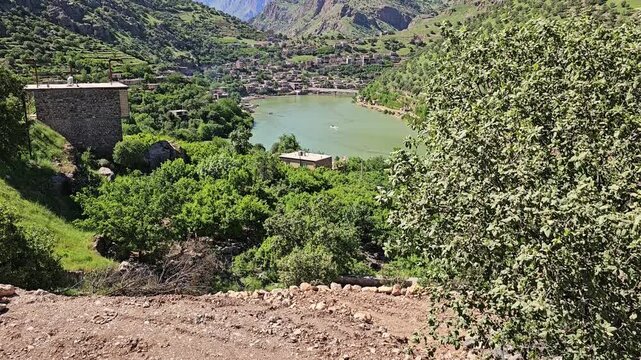 Calm green river winds through a sun-drenched mountain village, framed by terraced orchards and rugged spring peaks under a clear blue sky.
📍Selin village, Hawraman Takht, Kurdistan 