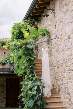 Lace Wedding Dress Hanging on Rustic Stone Staircase