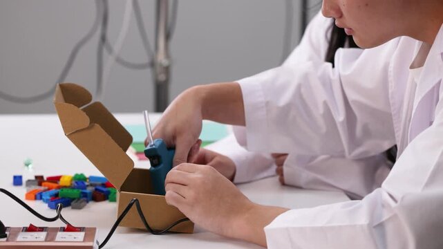 Teenage Student Using Hot Glue Gun for Science Project in Classroom