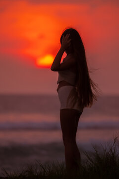 Silhouetted woman standing on the beach during a golden Sunset