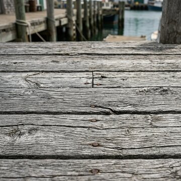 Weathered Wooden Pier Surface with Blurred Harbor Background.