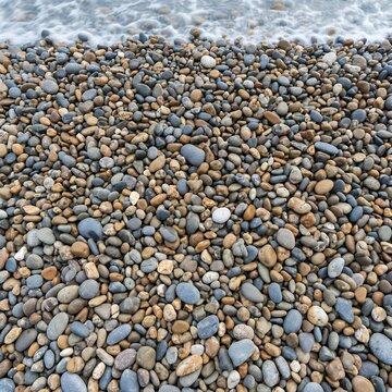Close up of a pebble beach with gentle waves lapping the shore.