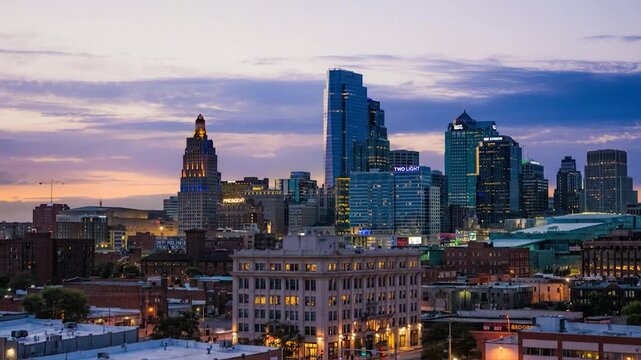 Kansas city skyline timelapse at sunset with illuminated buildings and moving cloud shadows.