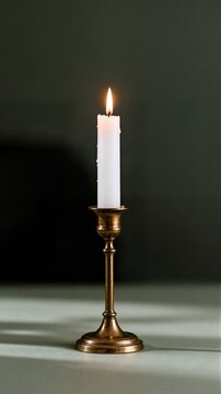 White burning candle in vintage bronze candlestick standing on surface ideal for spa luxury ambient lifestyle interior background concept