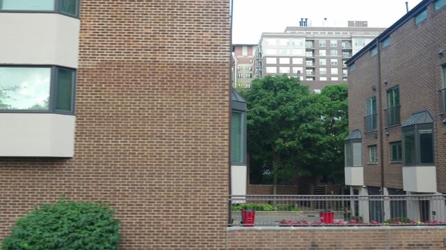 Modern brick apartment buildings with balconies and large windows in an urban residential area. The scene highlights contemporary city living with clean architectural lines and greenery.