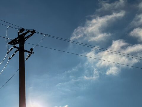 Wooden power pole with electrical wires against blue sky