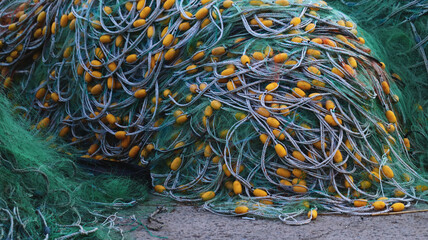 Piled Green Commercial Fishing Net with Yellow Floats and Ropes on Concrete at a Harbor © L.Z.C Photographer