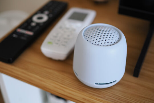 Small speaker on a wooden table next to remote controls