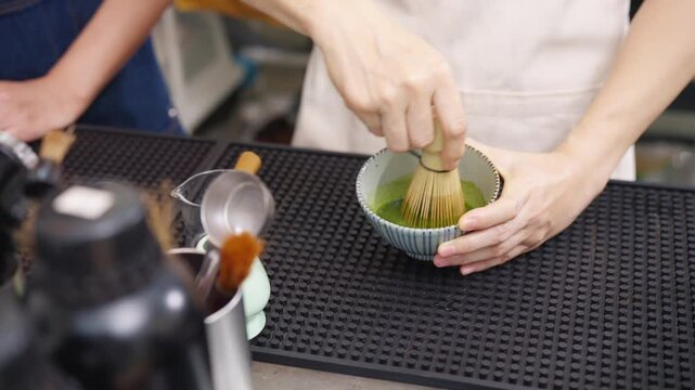 Barista preparing fresh iced green tea matcha to customer at cafe counter, professional beverage drink preparation specialty coffee and tea shop, small business hospitality and takeaway drink service