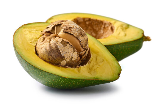 halved avocado with cracked seed isolated white background, green skin and yellow flesh with peeling brown pit, fresh produce ingredient in close-up view
