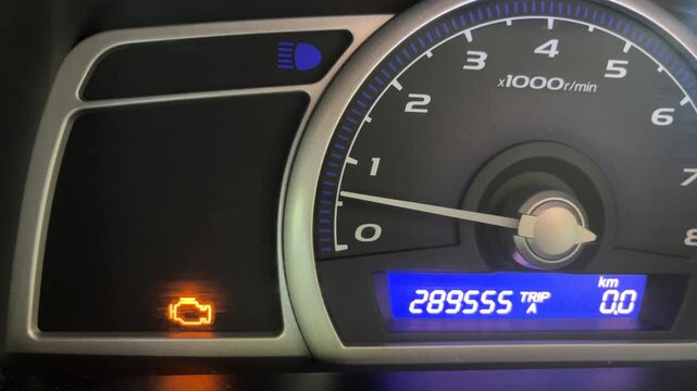 Car instrument panel with active check engine light and high mileage.