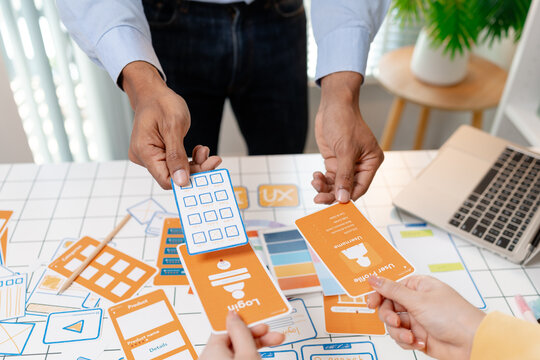 A UX design team collaborates with wireframes, interface cards, color palettes, and mobile app prototypes to improve user experience, design systems, product strategy, and digital innovation.