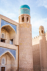 Historic watchtower with a turquoise tiled dome rising above the ancient walls of Khiva, Uzbekistan. Surrounded by beautifully preserved Islamic architecture, intricate blue mosaics © pploylp