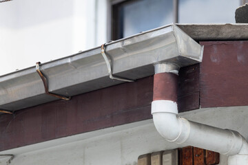 House gutter and downpipe in close-up view © Rattanachat