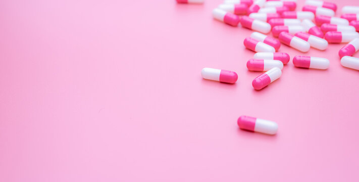 Pink-white antibiotic capsules pill spread on pink background. Antibiotic drug resistance concept. Antibiotic drug smart use. Antimicrobial drug. Health budget and policy. Pharmaceutical industry.