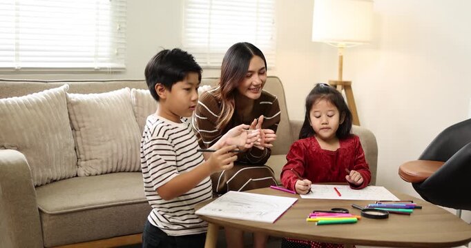 Working mother focusing on her laptop while her two young children are engaged in creative drawing activities, symbolizing a modern family balancing work and homelife