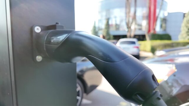 Electric car charging station cable attached to charger, sustainable energy transportation technology concept.