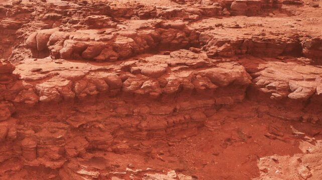Brown and red rocks form a rugged landscape in a desert area. The ground is dry with scattered stones. The scene shows the natural formation of the earth without any plants or animals.