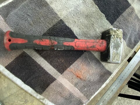 Worn sledgehammer with chipped handle covered in oil