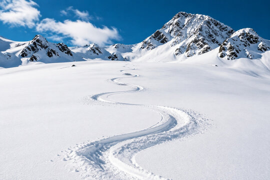 Snow-covered mountain slope with a single S-shaped ski track.
