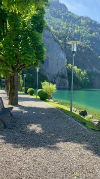 Peaceful lakeside park promenade with bench and green trees along Lake Lucerne in Canton of Uri Switzerland