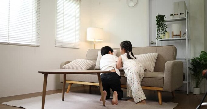 Asian mother sitting on the sofa, adjusting her son's red backpack before he leaves for school, illustrating a daily family routine and the nurturing aspect of parenting