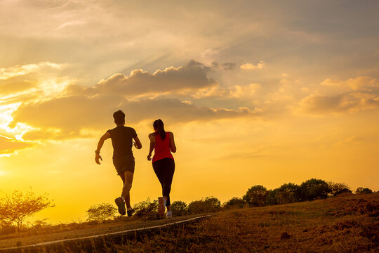 Silhouette of young couple running together on road across the bridge. Couple, fit runners fitness runners during outdoor workout