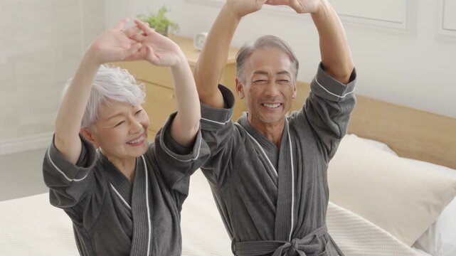 寝室でストレッチするシニア夫婦