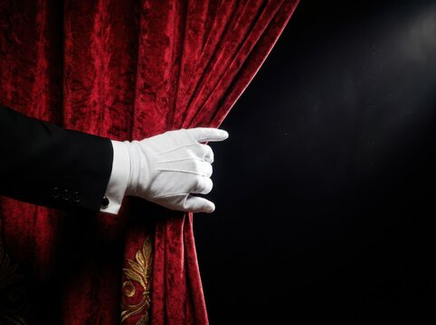 A Person In A Tuxedo Pulling Back A Luxurious Red Velvet Curtain