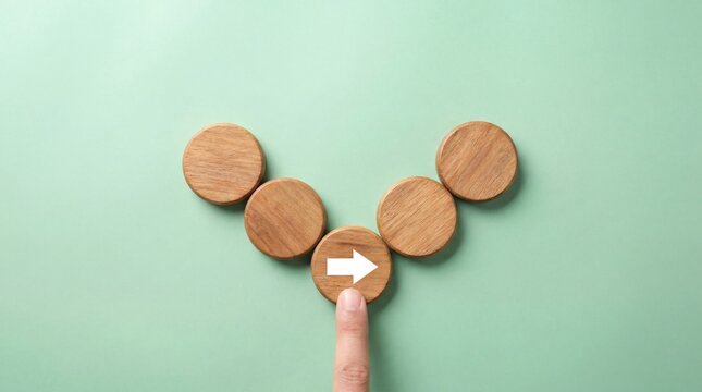 Finger pointing at wooden circle with arrow, choice and direction concept