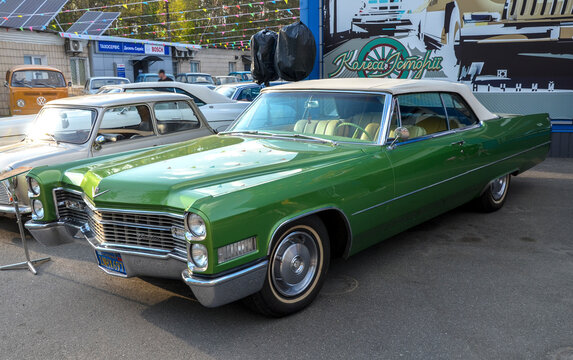 Cadillac DeVille luxury icon of American automotive culture. Emphasizes stunning emerald green paint, iconic stacked vertical headlights, and a massive chrome grille