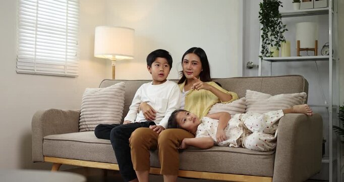 Asian mother engaging with her children, a boy and a girl, as they draw and color with marker pens on paper laid out on a low table, fostering a harmonious family environment