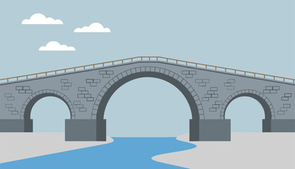 Fototapeta premium Majestic old stone arch bridge stretching over a winding blue river under a simple cloud filled sky.