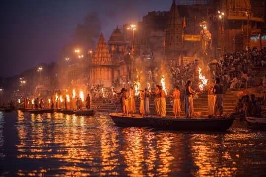 Spectacular Hindu Ganga Aarti ceremony happened at dusk on the Ganges River with many people performing rituals and holding flames in Varanasi, India