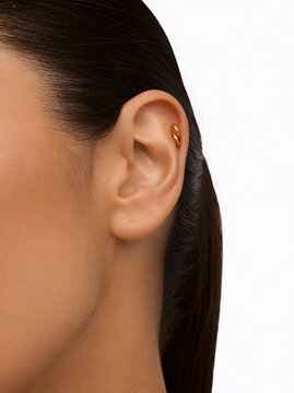 Close up of a woman ear showing a modern gold double helix piercing on white background
