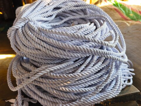 Large bundle of twisted white nylon rope coiled tightly together. Durable industrial cordage material photo for hardware supplies, marine equipment, packaging, or DIY craft concepts.