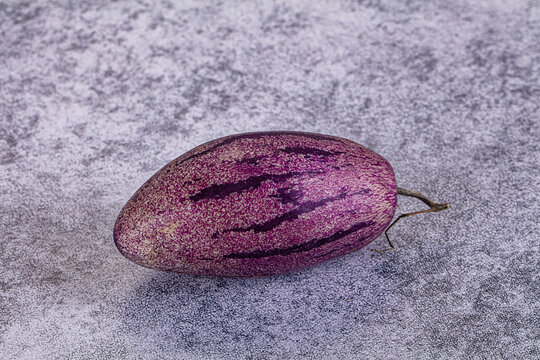 Exotic purple striped pepino melon on grey textured background