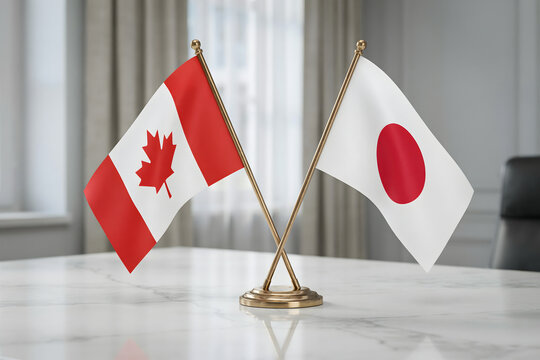 Small crossed flags of canada and japan displayed on a white marble conference table in a blurred office meeting room interior