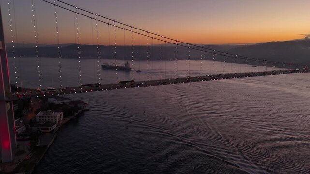 Istanbul Cityscape and Bosphorus Bridge (July 15 Martyrs Bridge) with big trafic. Aerial drone night view of the Bosphorus Bridge in sunrise. Ships passing Istanbul Canal or Bosphorus canal.
