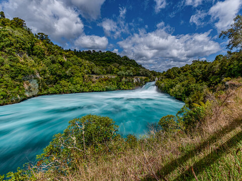 Huka Falls, Waikato River, Taupo, Neuseeland, Cyathea dealbata, reissender Wasserfall mit tuerkisfarbenem Wasser im Gruen der Natur, Langzeitbelichtung, Flusslauf, Tourismus