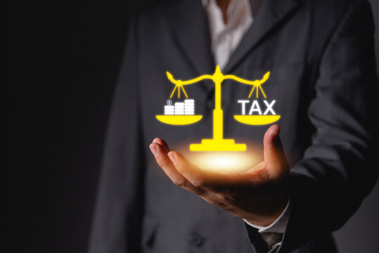 Businessman holding glowing virtual scale balancing tax text and money coins corporate financial planning wealth management and accounting compliance concepts for business taxation strategies