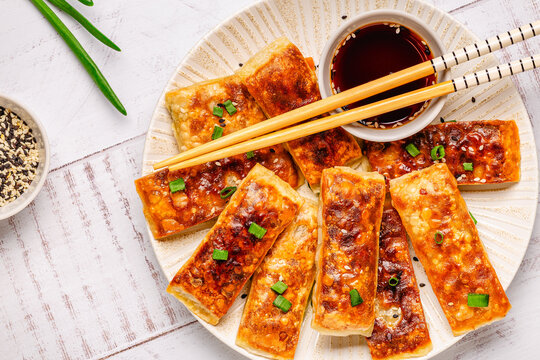 Dumplings are arranged on a plate with a small bowl of dipping sauce