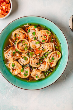 Dumplings served in a bowl with broth and green onions.
