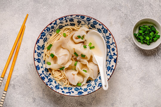 Noodles and dumplings wontons in bowl with green onions