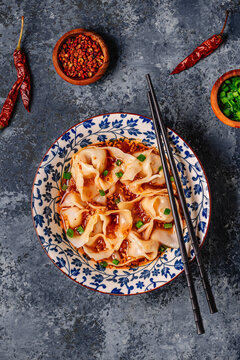 Wontons are placed in a bowl with spicy sauce.