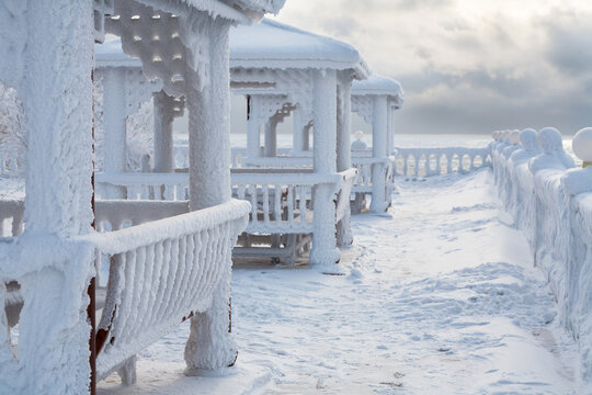 Frozen gazebos on the shore of Baikal Lake on a frosty winter day. Christmas holidays by coast of lake. Siberia, Irkutsk region,  Listvyanka village. Cold snowy landscape. Winter travels and outdoors
