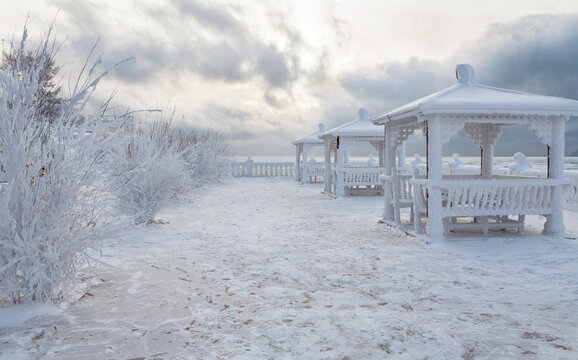 Deserted embankment of Baikal Lake at source of Angara River, with snowy gazebos, on frosty winter day. Christmas and New Year's holidays on lakeshore. Siberia, Irkutsk Region, Listvyanka village