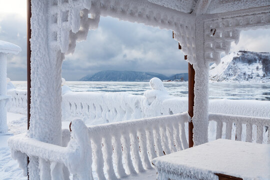 Embankment of Baikal Lake on frosty December day. View from frost covered wooden gazebo of source of Angara River. Winter travels on Christmas holidays. Siberia, Irkutsk, Listvyanka, Port Baikal